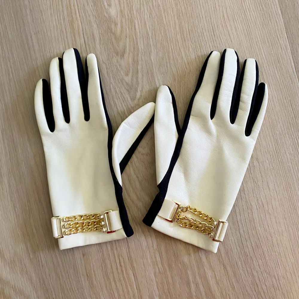 Små fina handskar med gulddetaljer Vita på handens baksida och svart i handflatan Passar handsorlek 7. Asusteet.
