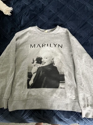 Sweatshirt  - Säljer den här gråa sweatshirten med ”Marilyn Monroe” motiv på🤗Den köptes för ett bra tag sen och har används en del, där av priset. Men den är fortfarande i ett väldigt bra skick!🫶🏻