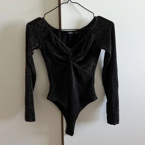 Långärmad glittrig body - Superfin långärmad svart body i guld glitter/stenar i storlek 36 (Small). Använt en gång. Mötas upp i Stockholm eller fraktas!