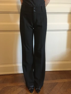 Utsvängda slim-fit byxor i svart - Utsvängda slim byxor ESPRIT i svart, med bredd hög midja.  Material: viskos, elastan. Storlek: 36.  Innersömslängd: 82 cm