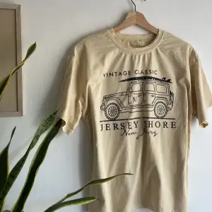 En T-shirt i beige/gult med tryck. Aldrig använd!