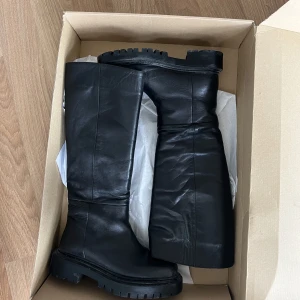 Höga boots - Säljer mina stövlar från NA-KD, sparsamt använda så i fint skick :) Storlek 37, men skulle snarare säga att de passar 38 då de är lite stora i storleken. Nypris ca 1000kr