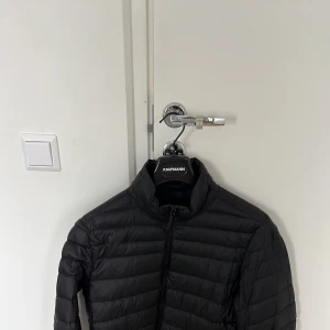 Svart dunjacka - Mango  - Svart dunjacka från märket Mango säljes i befintligt skick.  Strl L (skulle vilja säga Slimfit) passar även M. 