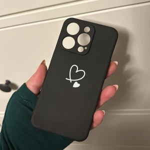 Svart mobilskal med vita hjärtan - iPhone 14 pro - Oanvänt mobilskal till iPhone 14 PRO. Svart med två vita hjärtan. Silikon-aktigt material.