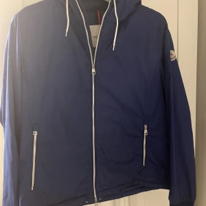 Moncler windbreaker - Moncler windbreaker: size medium  Moncler windbreaker med luva, cond 8/10.  Jackan är true to size, fast går att tighta till vid midja/mage eftersom att det finns snören på insidan av jackan.  Pris kan diskuteras vid snabb affär.