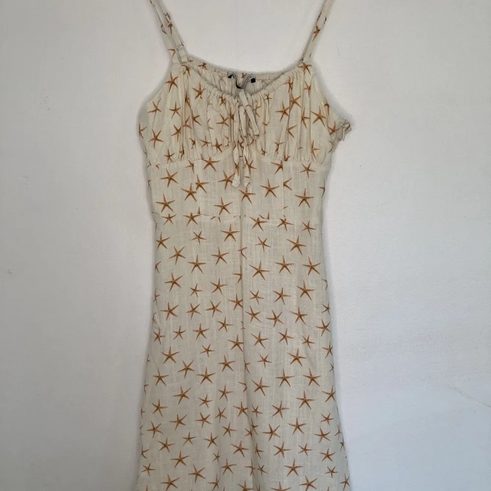 Petite klänning Storkel XS i vit linne, mönster med små sjöstjärnor. Använd en gång, säljer pga att den är för liten för mig.. Klänningar.