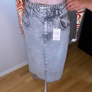 Säljer en helt oanvänd jeans kjol som är grå från MANGO i storlek M. 