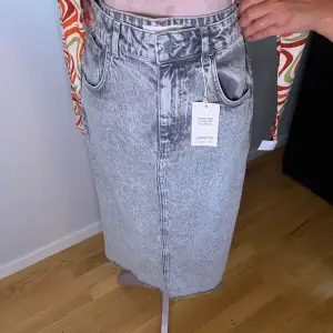 Säljer en helt oanvänd jeans kjol som är grå från MANGO i storlek M. 