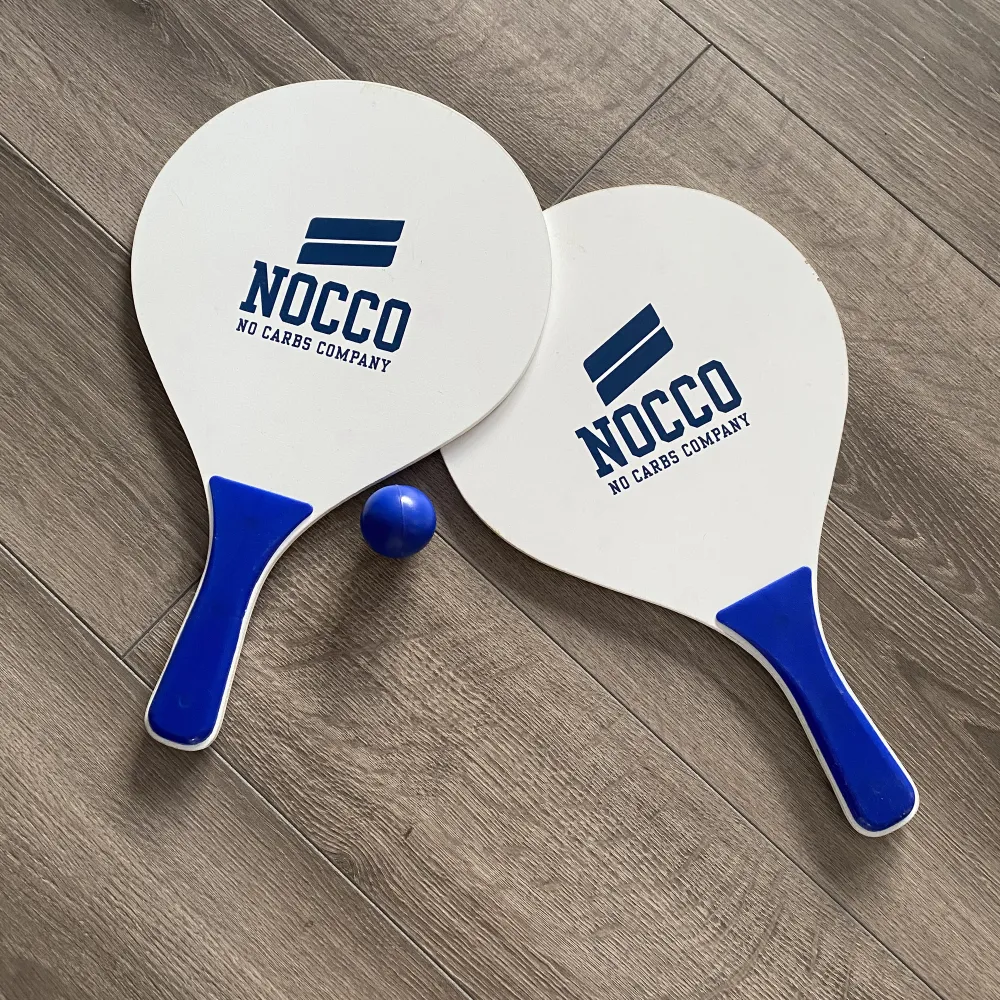 Nocco beachball racket och boll, har ej använts men det ena racket har ett minimalt kantstött märke (syns i bild). Går ej att få tag på, limiterad produkt. . Övrigt.