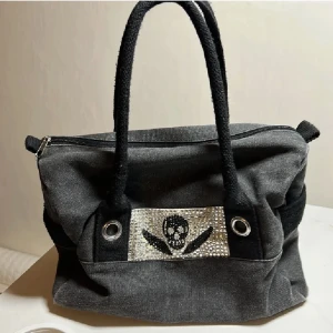 Handväska - FRI FRAKT! Super fin grå/svart väska med dödskalle i strass💗Den har ”rep” remmar som handtag. Den är ca 30 cm bred och ca 25 cm hög. För frågor eller fler bilder är det bara att höra av dig💗