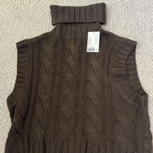 Stickad väst  - Brun stickad väst med polokrage. Aldrig använd och prislappen kvar.