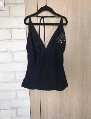 Halterneck top - Supersnygg halterneck topp med supergulliga blommor av paljetter på ena bröstet, i baddräktsmaterial vilket är otroligt skönt 