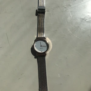 Klocka - Helt oanvänd klocka köpt på loppis. Inget batteri i. Lite beige/rosa färg på bandet blandat med vit. Fråga om fler bilder.