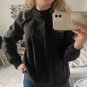 Blus - Svart blus med detaljer vid slutet på ärmarna och hals! Knappt använd!