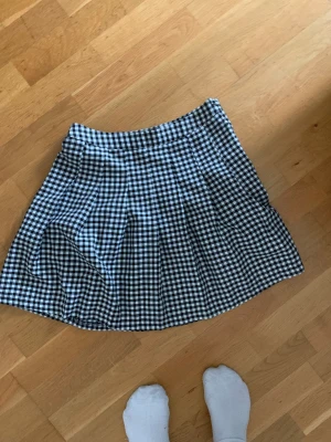 Rutig kjol - En svart vit rutig kjol från New Yorker. Kort i modellen. Stängs med dragkedja och knapp på sidan av kjolen.