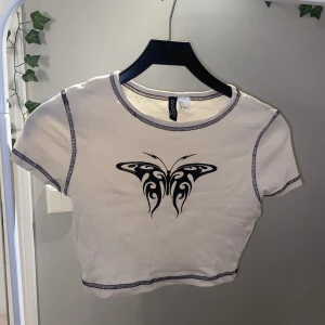 h&m croppad t-shirt - säljer denna croppade T-shirten från H&M för 50kr + frakt. Storlek S. den har lite sprickor i trycket, se andra bilden. Den har används fåtal gånger men slitits med åren. 