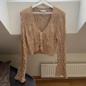 Långärmad Stickad topp - Långärmad topp i stickat material som man knyter i mitten. Den är i nyskick och har inga defekter, frakt tillkommer