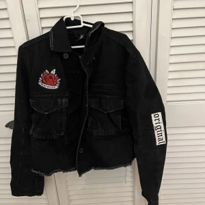 Svart jeansjacka - Svart croppad jeansjacka med broderingstryck! Endast använd få gånger så är i nyskick inprincip! Är i storlek 32 men passar mig som är xs/s perfekt!
