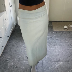 Lång ljus jeanskjol  - Snygg jeanskjol som knäpps med en dragkedja. Slits fram och bak. Mycket trendig och snygg. Vintage men obetydligt använd hel och ren. Står ingen storlek på lappen i kjolen men den uppskattas som en M. Personen på bilden är ca 170cm lång.