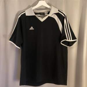 En fotbolls jersey av Adidas. Perfekt för en ”Blokecore” outfit. Lappen på tröjan säger ”Asian Large”, men passar mer som en medium.