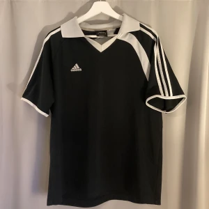 Adidas Fotbolls T-Shirt - En fotbolls jersey av Adidas. Perfekt för en ”Blokecore” outfit. Lappen på tröjan säger ”Asian Large”, men passar mer som en medium.