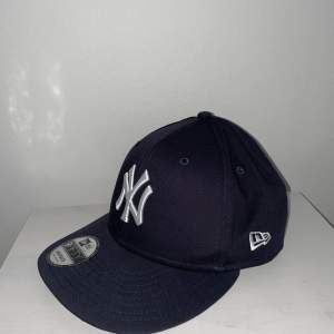 Mörkblå snapback keps från New Era med ”New York Yankees” logo. Storlek S-M. Aldrig använd.
