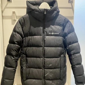 Sail racing Cloud dunjacka - Säljer en fin Sail racing Cloud dunjacka strl 170 (är som en S) i färgen carbon (svart).  Köpt förra vintern och använd endast en säsong.  Fläck på ena sidan som går bort i kemtvätt. 