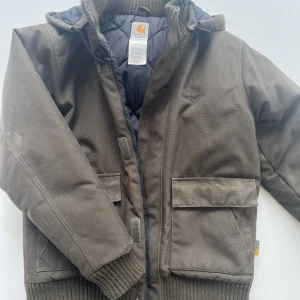 Carhartt vinterjacka  - Grön vinterjacka. Midjekort modell med luva
