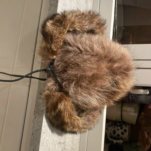 Pälsmössa - Mössa i äkta päls, passar bra på mig med ganska stort huvudet samt att snörena gör att de går att spänna åt