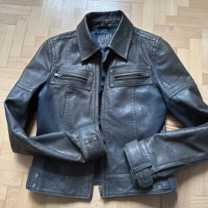 Vintage skinnjacka - Säljer min snygga vintage skinnjacka💞 Köpt på second hand💖 Säljer då den inte kommit till användning💗Det finns två defekter. Knappen på ena armen fattas och det är en liten fläck på högra sidan (se andra bilden) Men båda defekterna är inget man tänker på💕