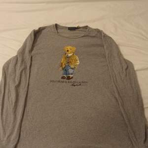 Grå långärmad från Ralph Laurens polo bear kollektion storleken är L men den sitter som en XL, något använd men sitter fortfarande som den ska. QR koden sitter fortfarande kvar.