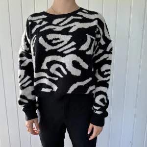 En stickad tröja i väldigt mjukt material. I vitt och svart zebra mönster. 