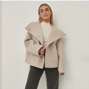 Kort kappa  - Säljer denna beige korta kappa ifrån NA-KD i storlek 32, helt slutsålda och ny med alla lappar kvar🤍