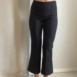 kostymbyxor 34 - Ankellånga bootcut/flare kostymbyxor från gina tricot. De är uppsydda för att passa min längd (164cm) men kan enkelt sprättas upp till originallängd då jag inte klippt av dem nåt. :)  Toppenskick, endast använda 1-2 ggr! 