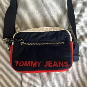 Väska - En liten väska ifrån tommy jeans som är knappt använd. Det vita partiet är lite smutsigt men annars är väskan som ny! Skriv för fler bilder, mått eller frågor👍🏻🫶🏻