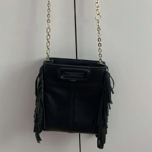 Maje väska Mini - En Maje väska i Mini storlek. Ett långt svart band, och en guldig kedja kommer till. (Hjälper syster att sälja) köpt på NK för - 2 400kr, säljer för - 1 500kr. Inga defekter. Hör av er för fler bilder.