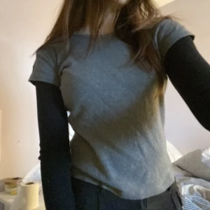 Grå och svart långärmad T-shirt - En T-Shirt med långa armar från Brandy Melville. Superskönt material och cool stil, perfekt till svalare sommar/hösten. Köptes på plick men kom aldrig till användning mer än 1 gång. Inga defekter och i superbra skick. Jag är 160cm med storlek xs/s.🩷🩷