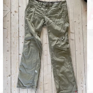 Cargobyxor m coola detaljer  - Cargo-byxor i mörkgrön. Low-waisted. Tajta och lite baggy runt låren och mer bell-bottom mot slutet. Kan ej visa bild då de är för små.  💘