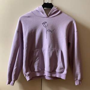 Säljer denna fina lavendel/lila hoodie med ros-tryck eftersom den är för liten. Den är använd några få gånger och är i bra skick! 