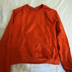 En röd/orange hoodie utan luva. Har lite fläckar på framsidan men dom syns inte jättemycket. Annars jätte skön, inte använd så mycket så den är i gott skick. Säljer då den inte kommer till användning längre 