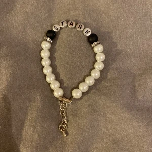 armband  - ett armband med orden ”stark” på, går att göra det lite större med hjälp av kedjan