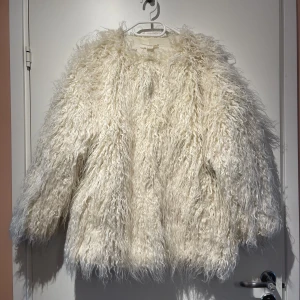 Vit fuskpäls - Vit jacka i fuskpäls. Jackan har fickor och stängs med ”krokar”. Den är i fint skick, endast använd nån enstaka gång! Dock har den fått lite sminkfläck uppe i kragen, men går troligtvis bort i en tvätt! 🤍