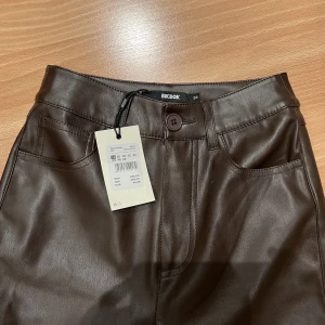 Bruna skinnbyxor - Bruna PU skinnbyxor från bikbok Aldrig använda då dem är lite för små för mig  High waist wide legs Nypris: 499kr Storlek 34 men väldigt stretchiga så passar även 36