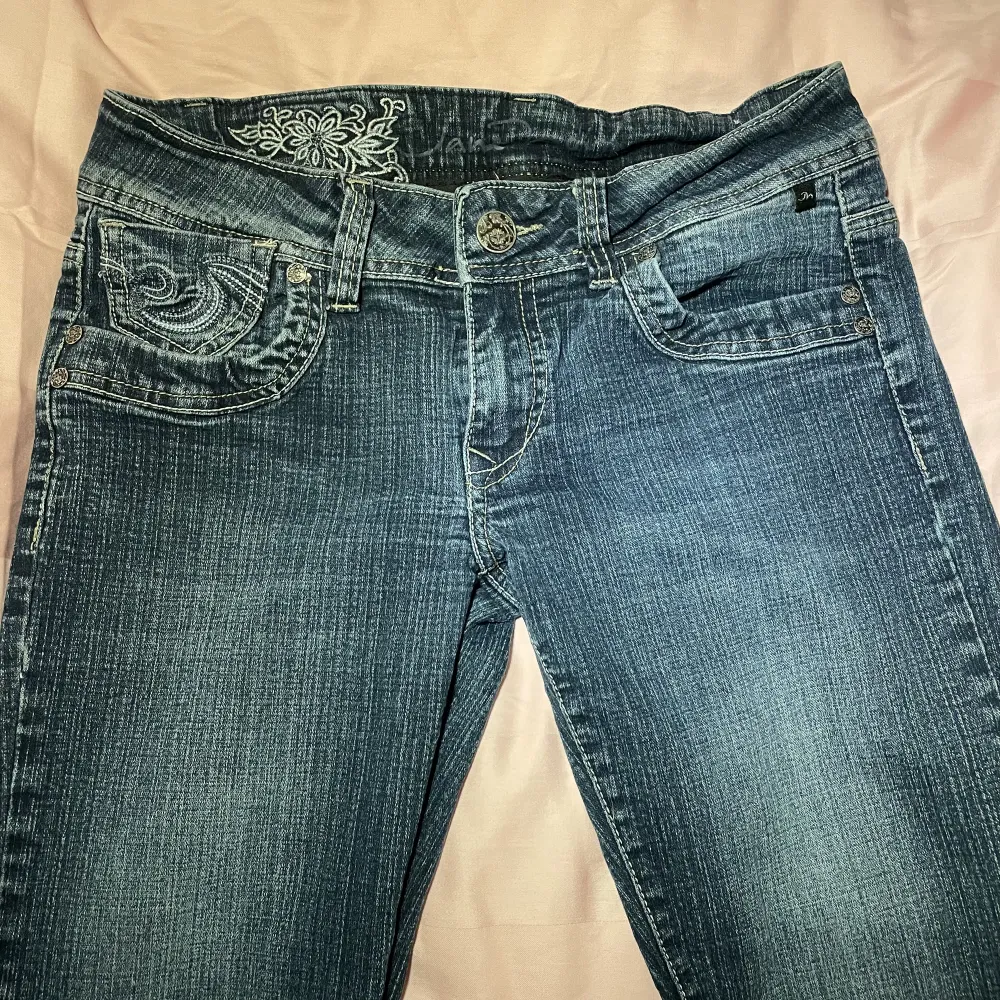 Mörkblå jeans i ett perfekt skick med jättecoola detaljer 💕 sitter lågmidjade och bootcut! Säljer för att de tyvärr är för korta på mig🥹. Jeans & Byxor.