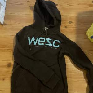 mörkbrun hoodie från wesc med ljusblå text, storlek xs!