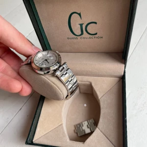 GUESS Collection Damklocka - Damklocka från GUESS Collection i väldigt fint skick, box i grönt krokodilskinn medkommer. Klockan är aldrig använd. Ställ gärna frågor om ni har några! 