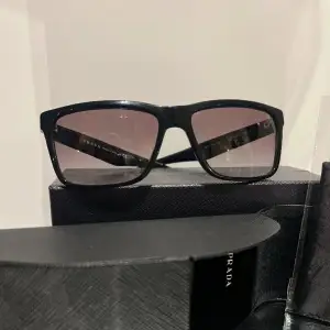 Solglasögon från Prada. Svarta med en mörklila ton på glaset. Använt väldigt sparsamt under en sommar. Topp skick med original förpackning samt kvitto. Ordinarie pris 2550kr.
