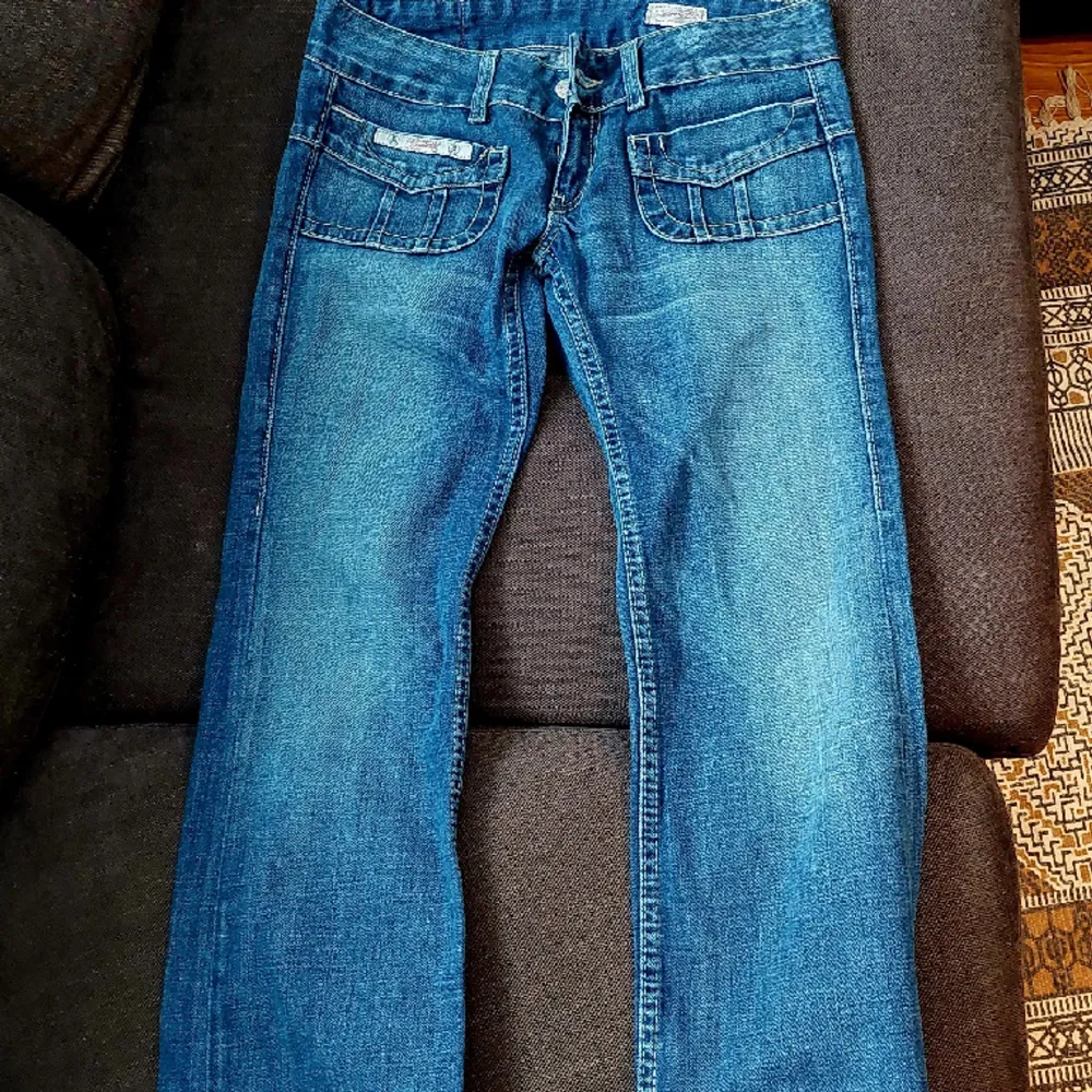 Blå flared lågmidjade jeans med snygga fickor. Strl 27-32. Jeans & Byxor.