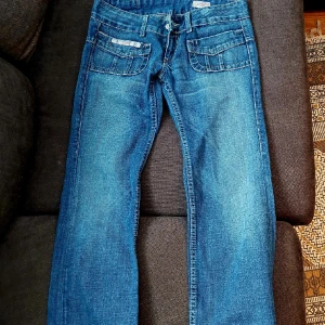 Y2k blå jeans - Blå flared lågmidjade jeans med snygga fickor. Strl 27-32