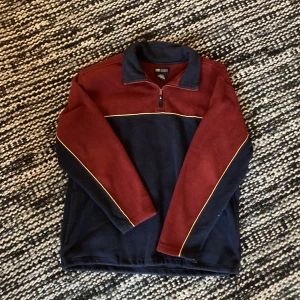 fleecetröja - Ascool vintage fleecetröja! Mörklblå och vinröd med gula detaljer. Halvzip och krage. Stl. L i herr, sitter som XL på mig. Varm och mysig, perfekt till hösten och vintern! Köpt second hand men i toppskick. Knappt använd av mig. Hör av dig vid intresse!!⭐️